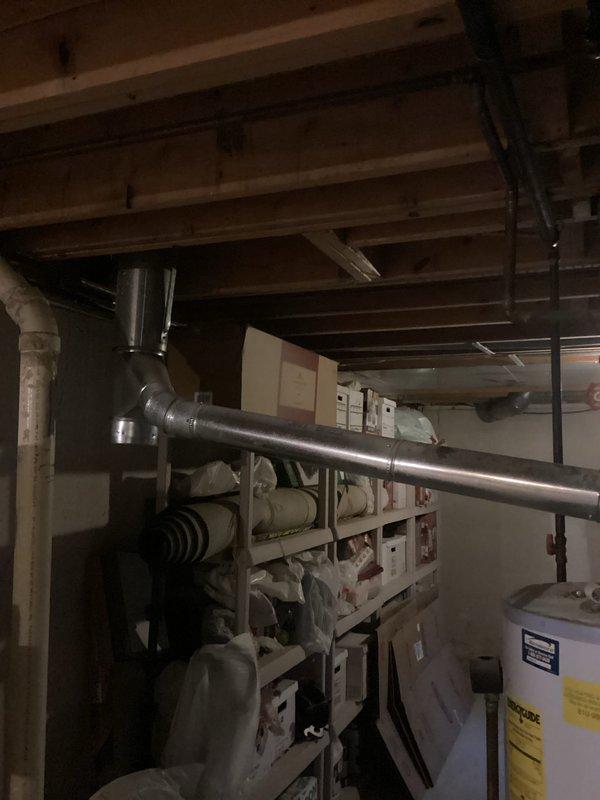 Technician responded to provide a humidifier estimate and identified an aging water heater requiring replacement. Documented the existing water heater installation in the basement utility area, noting the unit's condition and configuration alongside the HVAC system. Prepared comprehensive estimate for water heater replacement to address equipment age and prevent potential failure.