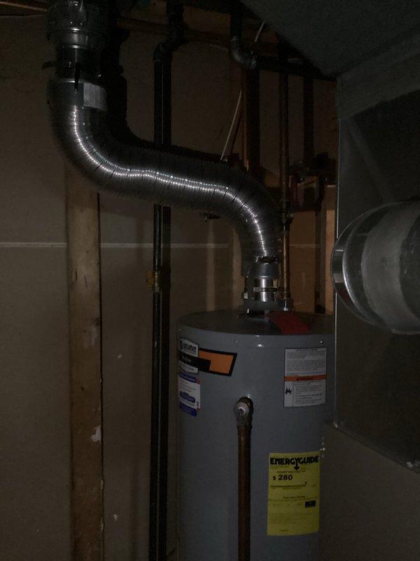 Conducted on-site water heater evaluation in residential basement utility space. Assessed existing cylindrical tank-style water heater installation, documented current equipment specifications, venting configuration with flexible aluminum ductwork, and associated plumbing connections including supply and discharge lines. Provided comprehensive estimate for water heater replacement options based on current system layout and mechanical room conditions.