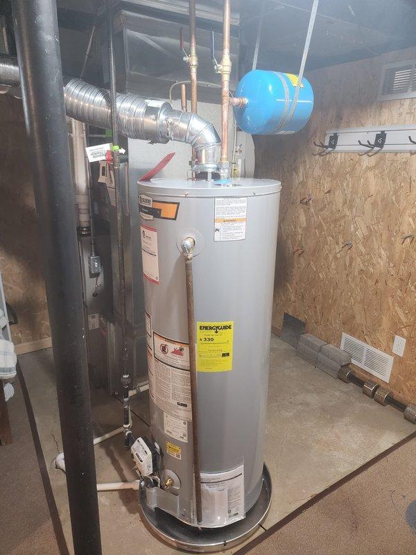 Replaced existing 50-gallon natural gas water heater with new unit in residential basement utility area. Disconnected and removed old water heater, then installed replacement unit with proper venting connections using flexible metallic ductwork. Connected copper supply and discharge lines to top of tank, ensuring secure fittings and proper water flow. Verified blue expansion tank remained properly mounted and integrated with new system. Tested all connections for leaks, confirmed proper gas line connection, and verified unit operation according to manufacturer specifications.