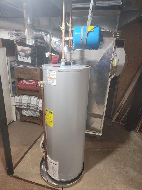 Replaced existing 50-gallon natural gas water heater with new unit in residential basement utility area. Disconnected and removed old water heater, then installed replacement unit with proper venting connections using flexible metallic ductwork. Connected copper supply and discharge lines to top of tank, ensuring secure fittings and proper water flow. Verified blue expansion tank remained properly mounted and integrated with new system. Tested all connections for leaks, confirmed proper gas line connection, and verified unit operation according to manufacturer specifications.
