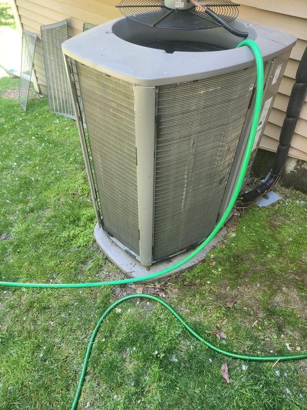 Completed routine maintenance on residential air conditioning system. Performed condenser coil cleaning using water hose to remove debris and ensure optimal heat transfer efficiency. Inspected refrigerant lines, electrical connections, and internal components through access panel, verifying proper wire routing and system integrity. Unit operational and ready for cooling season.