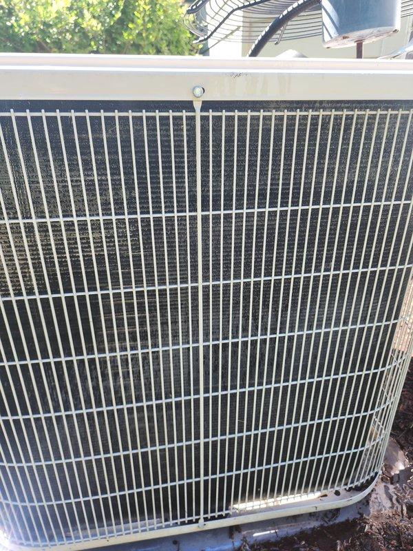 Completed scheduled maintenance on residential air conditioning system. Performed comprehensive inspection of outdoor condenser unit, noting accumulated dirt and debris on coil fins and interior components. Cleaned condenser coils, removed environmental debris from unit base and interior compartment, and inspected compressor housing, refrigerant lines, and electrical connections. System operational and cooling properly upon completion of maintenance service.