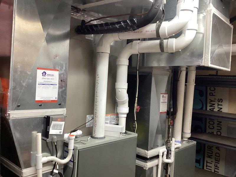 Completed commercial air conditioning installation featuring a new Lennox condensing unit mounted on exterior pad with proper electrical disconnect and connection to existing air handler system. Installation included refrigerant line set routing, condensate drainage via PVC piping network, and verification of all electrical connections and system operation to manufacturer specifications.
