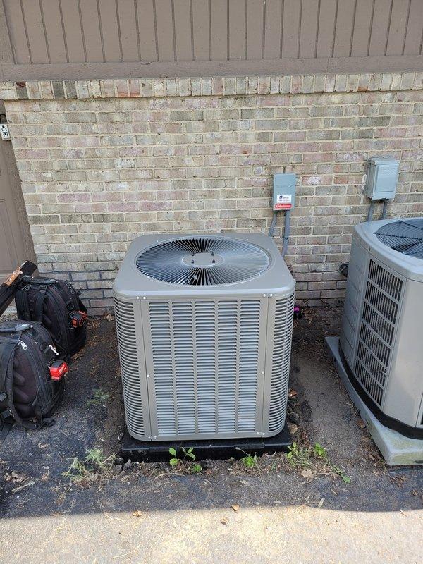 Completed commercial air conditioning installation featuring a new Lennox condensing unit mounted on exterior pad with proper electrical disconnect and connection to existing air handler system. Installation included refrigerant line set routing, condensate drainage via PVC piping network, and verification of all electrical connections and system operation to manufacturer specifications.