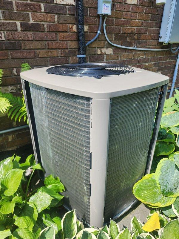 Completed scheduled prepaid maintenance tune-up on residential cooling system. System operational and functioning properly upon arrival. Performed comprehensive inspection of outdoor condenser unit located at exterior brick wall, surrounded by landscaping. Inspected compressor, refrigerant lines, electrical connections, and coil assembly. Noted normal condensation present on compressor and internal components, indicating proper system operation during cooling cycle. All copper refrigerant lines, electrical wiring, and disconnect components inspected and found secure. System tested and confirmed working within normal operating parameters.