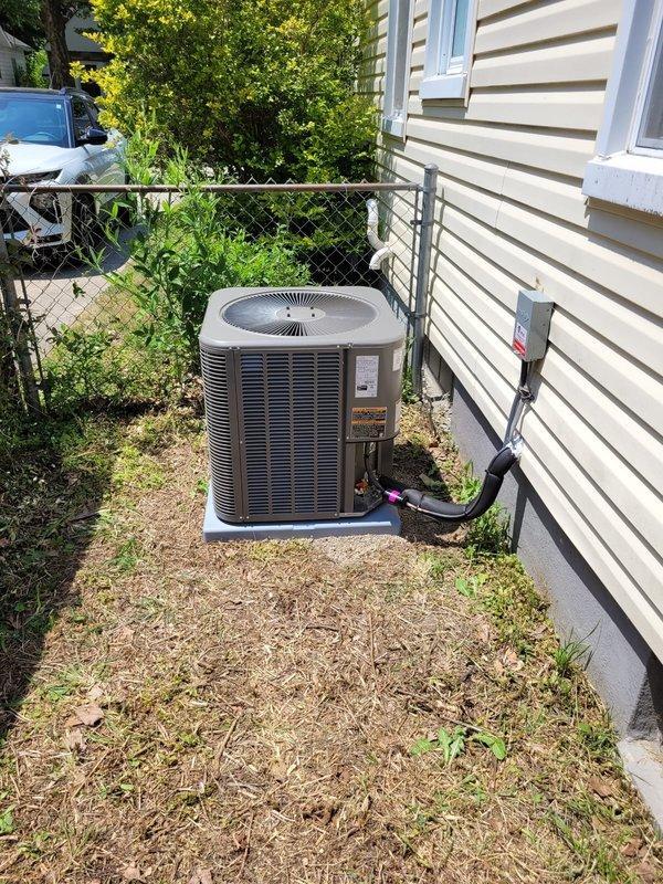 Completed installation of Lennox air conditioning condenser unit at residential property. Unit was positioned on concrete pad against exterior wall with proper electrical disconnect box mounted and refrigerant lines run through siding into home. System was tested and verified operational upon completion.