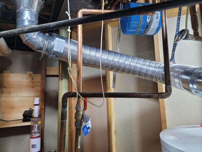 Completed installation of 50-gallon tanked water heater in basement utility area. Removed existing whole-house water filter system per sales agreement and proceeded with new water heater setup. Installed unit with proper seismic strapping at base for code compliance and safety. Connected water supply lines using appropriate piping configurations, including PVC discharge piping with T-junction setup at floor level. Verified all connections to existing copper supply lines and gas shutoff valve assembly. Ensured proper clearances around unit and confirmed all manufacturer specifications were met during installation. System tested and operational upon completion.