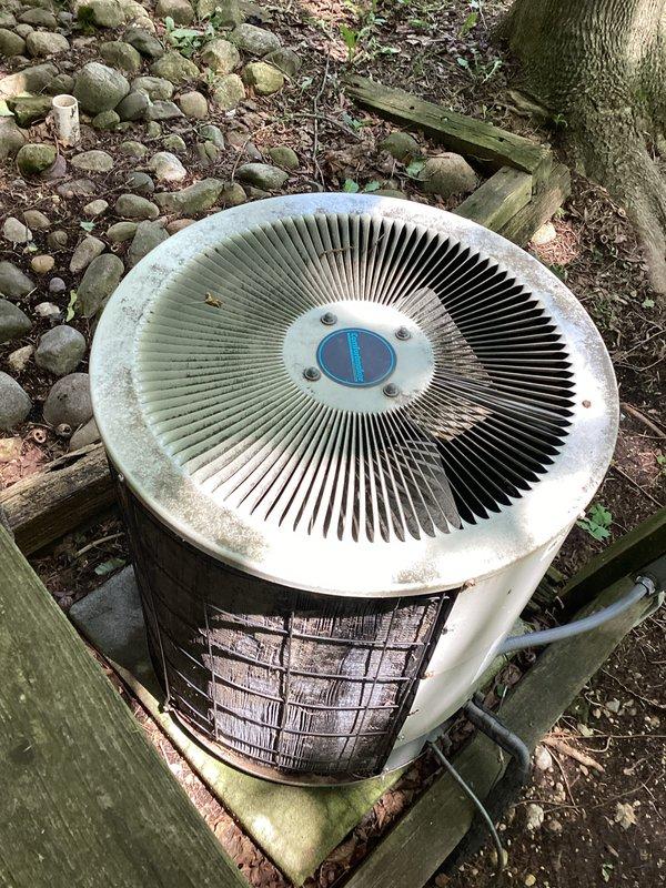Evaluated a 28-year-old R22 air conditioning system with a failed condenser fan motor. Documented the outdoor condenser unit showing significant age-related weathering and the indoor furnace system, and provided an estimate for condenser fan motor replacement to restore cooling functionality.