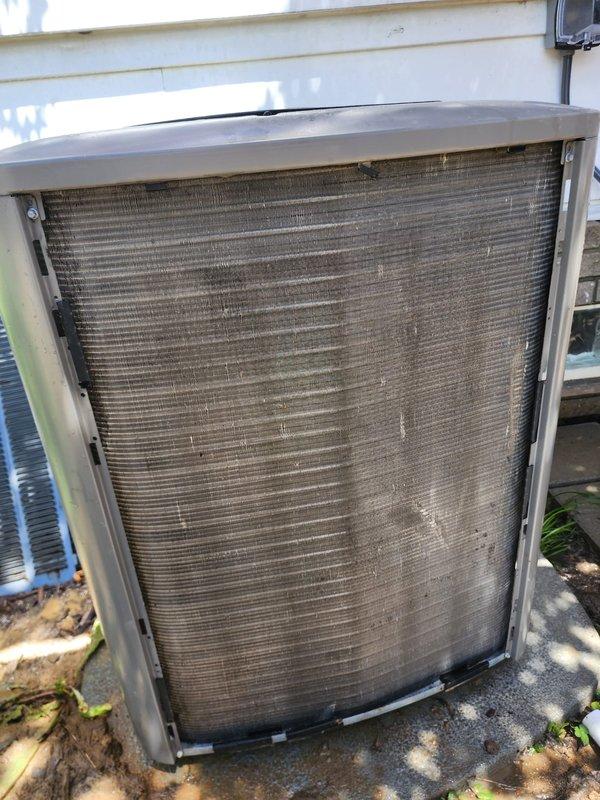 # HVAC Maintenance - Cooling System Service

Performed comprehensive seasonal tune-up and maintenance on residential cooling system. Upon arrival, confirmed system was operating properly with no reported performance issues. Conducted thorough inspection of outdoor condenser unit, noting significant accumulation of dirt, dust, and debris on protective grille and condenser coil fins. Documented condition of unit exterior showing vegetation and organic matter around base perimeter.

Inspected internal components including compressor assembly, refrigerant lines, and electrical connections. Verified proper operation of cylindrical compressor unit with copper refrigerant tubing configured in standard loop arrangement. Examined electrical wire harness connections at compressor terminal, confirming secure attachment of multi-colored conductors. Assessed condition of condenser coil with parallel fin arrangement, noting accessibility within foam-insulated housing compartment.

Evaluated copper r