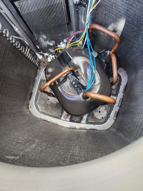 # HVAC Maintenance - Cooling System Service

Performed comprehensive seasonal tune-up and maintenance on residential cooling system. Upon arrival, confirmed system was operating properly with no reported performance issues. Conducted thorough inspection of outdoor condenser unit, noting significant accumulation of dirt, dust, and debris on protective grille and condenser coil fins. Documented condition of unit exterior showing vegetation and organic matter around base perimeter.

Inspected internal components including compressor assembly, refrigerant lines, and electrical connections. Verified proper operation of cylindrical compressor unit with copper refrigerant tubing configured in standard loop arrangement. Examined electrical wire harness connections at compressor terminal, confirming secure attachment of multi-colored conductors. Assessed condition of condenser coil with parallel fin arrangement, noting accessibility within foam-insulated housing compartment.

Evaluated copper r
