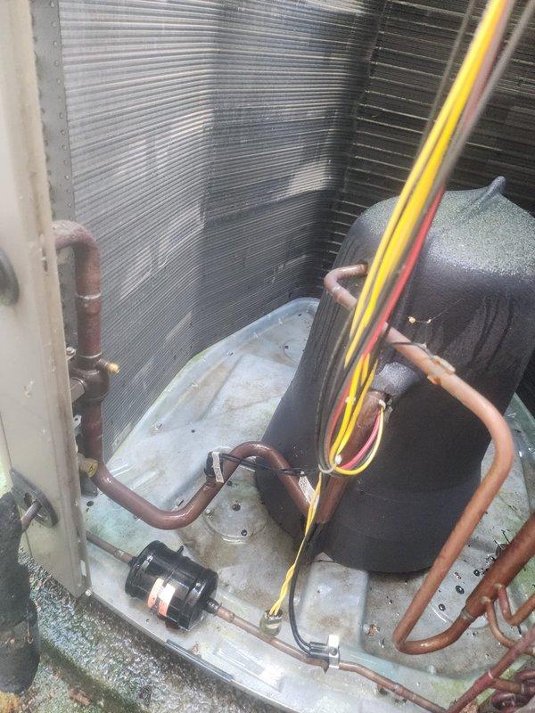 Responded to no cooling complaint on Lennox condensing unit. Upon arrival, confirmed outdoor fan motor was not operating while compressor attempted to run. Inspected unit exterior showing signs of age and environmental exposure with algae growth on pad and weathering on cabinet. Removed top panel and diagnosed failed condenser fan motor. Motor tested with no continuity and showed signs of bearing failure. Replaced defective fan motor with OEM equivalent, verified proper rotation and amperage draw within specifications. Checked capacitor values and found dual run capacitor reading low on fan side; replaced capacitor to ensure reliable operation. Cleaned condenser coils of accumulated debris and dust buildup to restore proper airflow and heat transfer efficiency. Verified all refrigerant line connections secure with no visible signs of leakage. Tested system operation through complete cooling cycle, confirmed proper compressor function, adequate airflow across coil, and temperature split