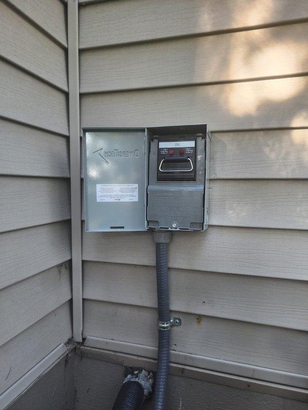 Responded to warranty call for missing dead front cover on outdoor A/C disconnect box. Upon arrival, found DiversiTech electrical disconnect enclosure mounted on exterior wall with cover panel removed, exposing internal fuse holders, terminal connections, and wiring. Inspected installation and verified all electrical connections were secure with proper wire routing through conduit. Confirmed disconnect box functionality and proper operation of safety components. Documentation photos captured current condition of unit showing open enclosure with visible terminal blocks, fuse holders, and color-coded wiring properly installed through flexible conduit. Unit remains operational pending replacement cover installation.