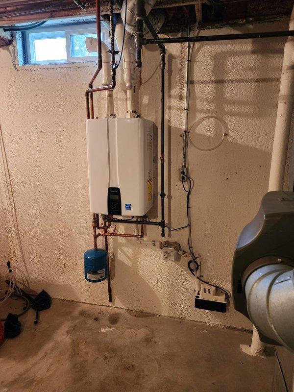 Successfully installed wall-mounted tankless water heater unit in basement utility area with spray foam insulated walls. Converted exhaust system from standard venting to PVC piping as specified, and completed all copper supply line connections with proper hot and cold water plumbing integration. Installed blue expansion tank on copper piping system below the unit to protect against thermal expansion and maintain system pressure. Verified all electrical connections, tested unit operation, and confirmed proper venting through new PVC exhaust system.