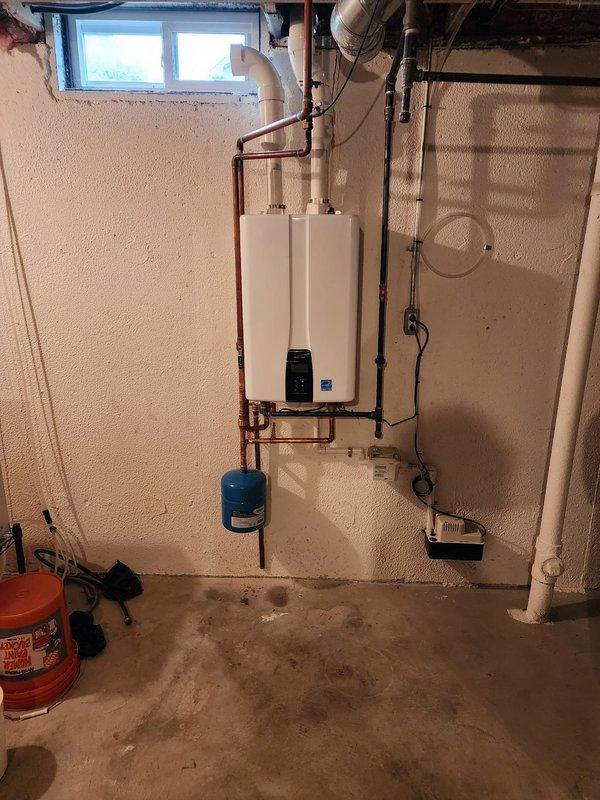Successfully installed wall-mounted tankless water heater unit in basement utility area with spray foam insulated walls. Converted exhaust system from standard venting to PVC piping as specified, and completed all copper supply line connections with proper hot and cold water plumbing integration. Installed blue expansion tank on copper piping system below the unit to protect against thermal expansion and maintain system pressure. Verified all electrical connections, tested unit operation, and confirmed proper venting through new PVC exhaust system.