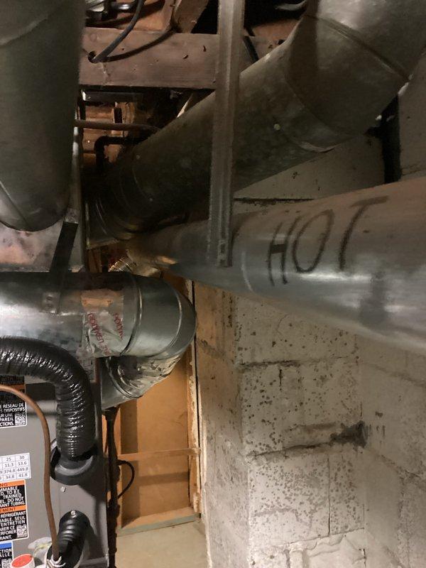 Conducted on-site assessment for water heater replacement in basement utility area. Existing Defender brand water heater evaluated for replacement, with documentation of current installation including copper supply piping and overhead plumbing connections. Noted deteriorating fiberglass insulation in ceiling area above unit requiring attention during installation. Photographed existing equipment, ductwork configuration, and mechanical room layout to prepare accurate replacement estimate.