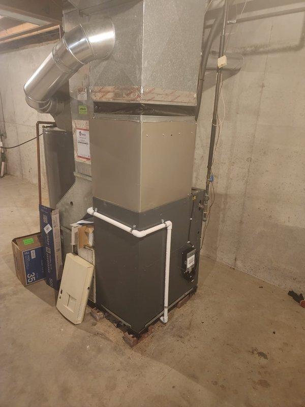Completed installation of Bryant air conditioning system in residential basement mechanical room. New AC unit installed and connected to existing furnace infrastructure with proper ductwork integration and electrical connections. Service financing documentation processed and customer identification verified on file.