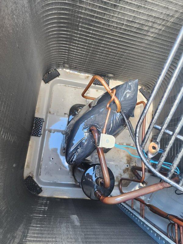 # Annual Cooling System Maintenance

Performed comprehensive annual maintenance on residential air conditioning system. Unit was operational upon arrival with no reported issues. Conducted complete inspection of outdoor condenser unit, which is positioned on gravel pad in good overall condition showing normal weathering. Examined heat exchanger coils with bronze-colored fins arranged in vertical rows - coils appear functional with typical outdoor aging present.

Inspected internal components including condensate drain pan showing normal wear and discoloration consistent with regular use. Evaluated refrigerant lines of varying diameters with characteristic copper patina. Noted black foam insulation on copper piping sections with some deterioration present - typical for systems of this age. All refrigerant lines properly routed and secured.

Verified electrical connections and conduit routing. Checked system operation and confirmed proper cooling function. System performing within normal