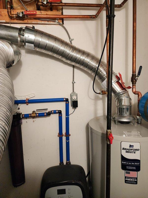 Completed installation of 40-gallon Bradford White tanked water heater in residential utility room. Connected copper supply lines with shut-off valves, installed expansion tank, integrated unit with existing HVAC ductwork, and verified all plumbing connections, drain valve, and electrical components for proper operation.