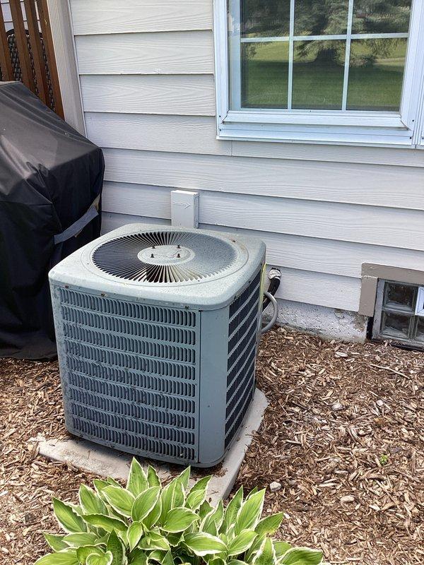 Provided estimate for complete air conditioning system replacement at residential property. Current outdoor condenser unit and indoor air handler are non-operational, with equipment age estimated to match home construction date. Assessment included evaluation of existing basement-mounted air handler with PVC condensate drainage system and exterior condenser unit positioned on concrete pad against home's foundation.