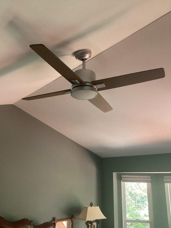 Completed ceiling fan repair in residential bedroom. Serviced five-blade ceiling fan with integrated light fixture, addressing operational issues. Verified proper function of fan controls including multi-button smart control panel and standard rocker switches on triple-gang wall plate. All components tested and confirmed working properly upon completion.