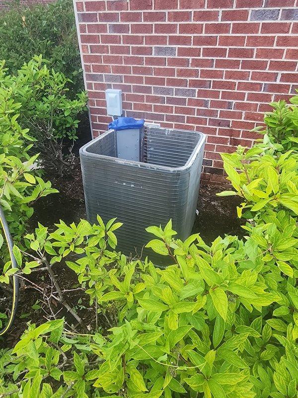 # HVAC Service Report - No Cooling Condition

Responded to service call for air conditioning unit not cooling. Upon arrival, found outdoor condenser unit located against brick exterior wall with landscaping surrounding the equipment. 

Removed top access panel to inspect internal components. Found 10+ year old unit with black cylindrical compressor, copper refrigerant lines, and U-shaped aluminum fin evaporator coil running perimeter of cabinet. Noted significant dust accumulation on coil surfaces and dirt buildup on interior base and compressor mounting area. Unit showed visible signs of age with weathering on components and some surface oxidation present.

Performed diagnostic inspection of compressor, electrical connections (red, yellow, and white wiring), and refrigerant lines. Assessed overall condition of evaporator coil with tightly-spaced aluminum fins. Documented equipment condition and findings with photographs for service records.

Given the age of the unit (10+ years) and o
