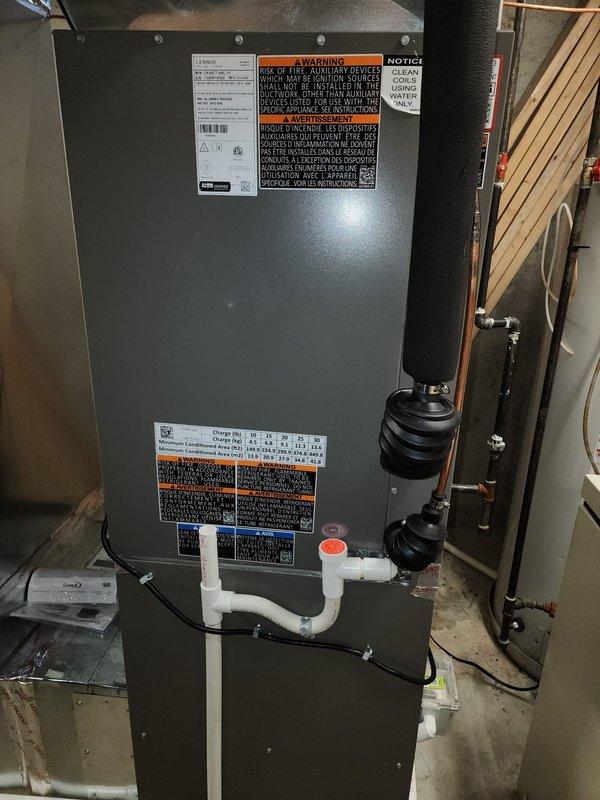 Completed full HVAC system installation including Lennox furnace air handler, air conditioner condenser unit, and T6 programmable thermostat. Installed indoor air handler in basement utility area with proper refrigerant line connections, condensate drainage system using white PVC piping, and integrated ductwork connections. Positioned outdoor condenser unit at building exterior with appropriate clearances from structure and landscaping, ensuring proper drainage and ventilation access.