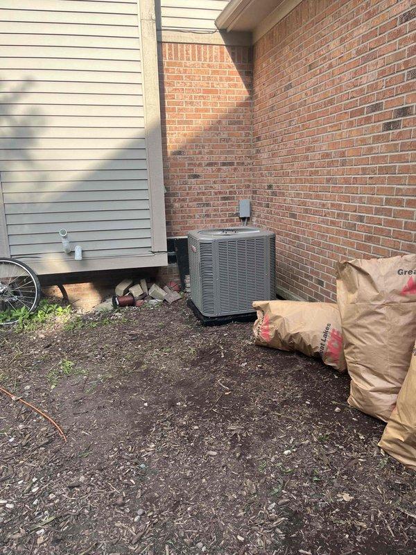 Completed full HVAC system installation at residential property. Installed new outdoor condensing unit on concrete pad against exterior brick wall with proper clearances maintained. Mounted electrical disconnect box on brick wall above condenser unit. Routed refrigerant lines and electrical connections between outdoor unit and indoor air handler. System tested and verified operational with all electrical connections secured and properly terminated. Installation meets manufacturer specifications and local code requirements.