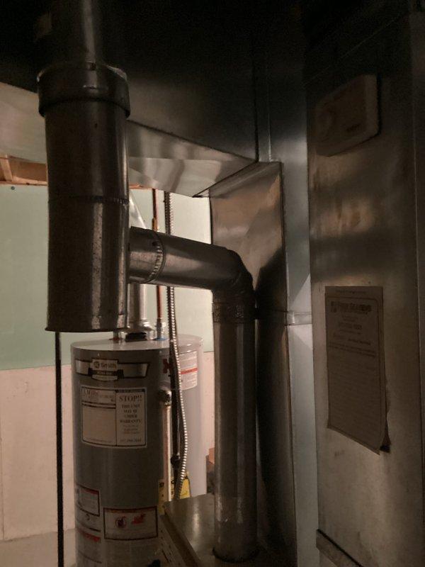 Conducted on-site evaluation of 28-year-old residential central air conditioning system originally installed in 1998. System currently operational but showing signs of declining performance. Assessed outdoor condenser unit and indoor evaporator coil configuration in basement mechanical room. Documented existing HVAC infrastructure including air handler, ductwork, and electrical connections. Photographed equipment placement and surrounding mechanical systems to prepare comprehensive replacement estimate for complete AC system upgrade.