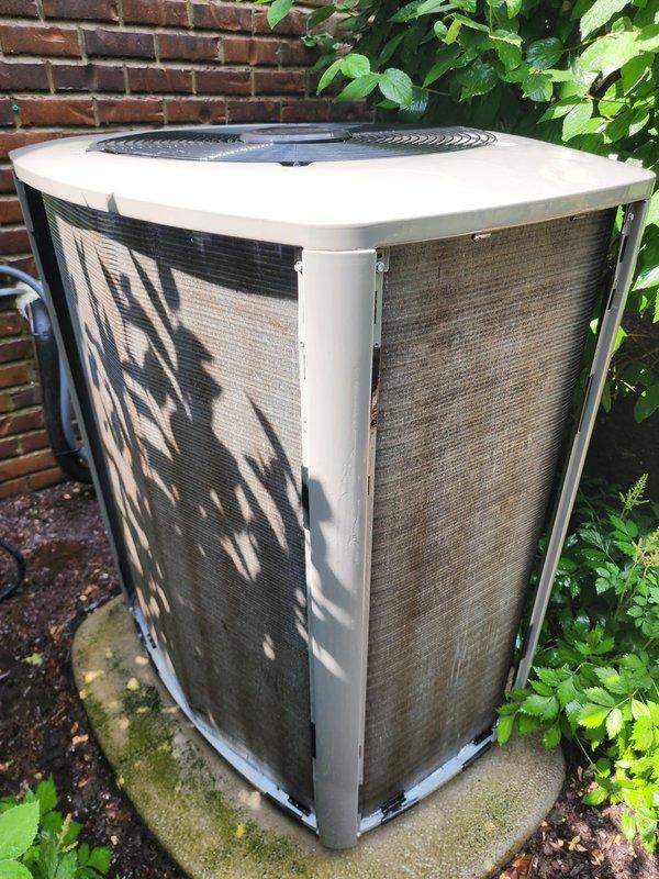 # HVAC Maintenance - Cooling System Service

Performed comprehensive seasonal tune-up and maintenance on residential central air conditioning system. Unit was fully operational upon arrival. Conducted complete system inspection including outdoor condenser unit positioned on concrete pad against exterior brick wall. Inspected cabinet condition, protective mesh screening, and fan grille assembly. 

Examined internal components including heat exchanger coils, condenser coils with metallic fin assemblies, and compressor unit. Verified integrity of copper refrigerant lines showing normal oxidation patina. Inspected electrical wiring connections including multi-colored conductor bundle with proper insulation. Checked component mounting, base plate assembly, and U-bend refrigerant line configuration.

Assessed outdoor unit placement on moss-covered concrete pad with surrounding mulched area. Noted leaf debris accumulation on protective screening from nearby vegetation. System confirmed operat