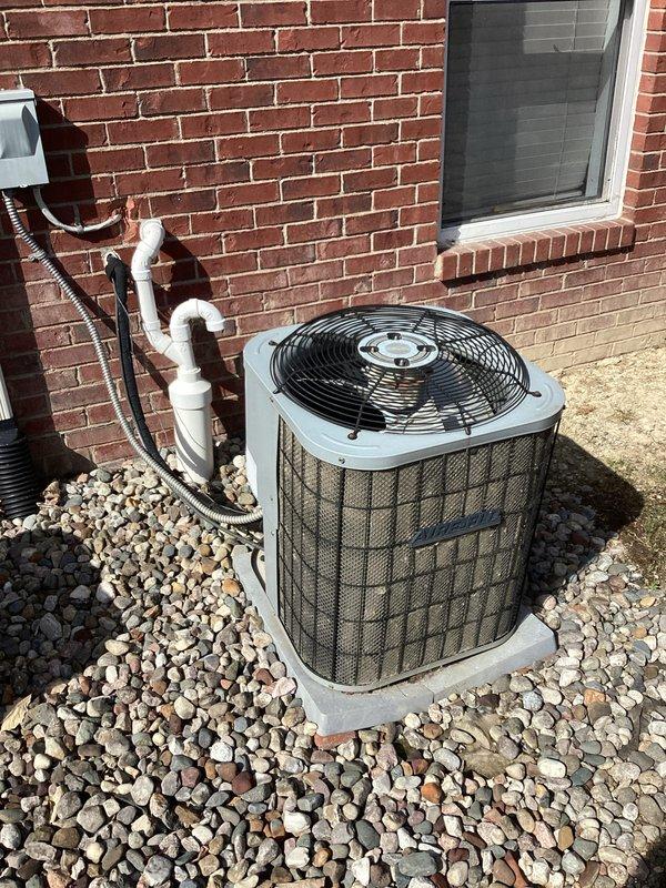 Completed estimate for replacement of aging residential air conditioning system. The existing outdoor condensing unit, positioned on a concrete pad with river rock landscaping against brick exterior, is over 20 years old and had major repairs performed by another contractor last year. Assessed current equipment condition, photographed existing installation including refrigerant line routing, electrical disconnect boxes, and unit placement. Provided homeowner with replacement options and pricing for new HVAC system installation.