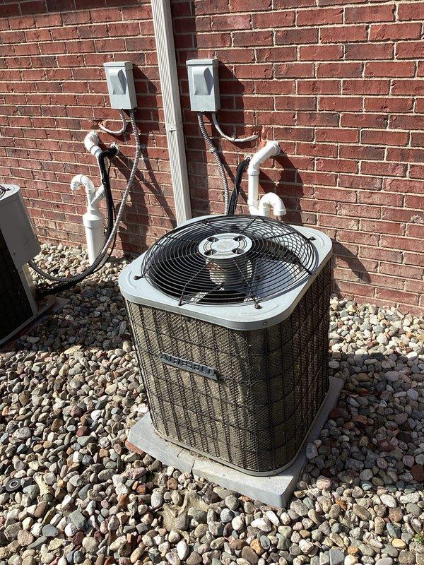 Completed estimate for replacement of aging residential air conditioning system. The existing outdoor condensing unit, positioned on a concrete pad with river rock landscaping against brick exterior, is over 20 years old and had major repairs performed by another contractor last year. Assessed current equipment condition, photographed existing installation including refrigerant line routing, electrical disconnect boxes, and unit placement. Provided homeowner with replacement options and pricing for new HVAC system installation.