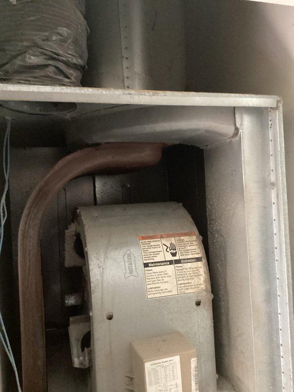 Completed HVAC system replacement estimate for residential unit with failed blower motor. Upon inspection, determined repair costs would exceed recommended threshold for economical repair. Assessed both indoor air handler component mounted in attic space and outdoor condensing unit located in side yard between structures. Indoor unit showed normal wear and dust accumulation with refrigerant lines properly connected. Outdoor unit positioned on soil base in confined area with visible debris accumulation and vegetation encroachment around perimeter. Documented existing system condition through photographs of both components to support replacement recommendation over costly motor repair.