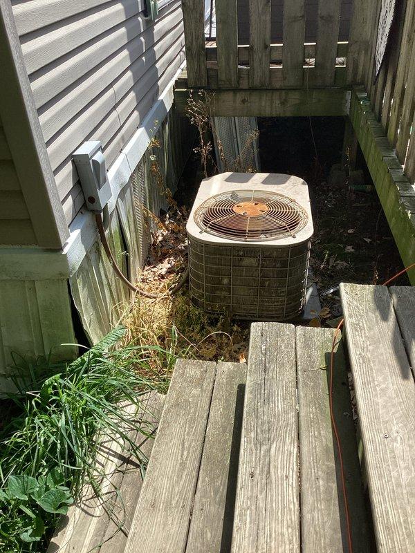 Completed HVAC system replacement estimate for residential unit with failed blower motor. Upon inspection, determined repair costs would exceed recommended threshold for economical repair. Assessed both indoor air handler component mounted in attic space and outdoor condensing unit located in side yard between structures. Indoor unit showed normal wear and dust accumulation with refrigerant lines properly connected. Outdoor unit positioned on soil base in confined area with visible debris accumulation and vegetation encroachment around perimeter. Documented existing system condition through photographs of both components to support replacement recommendation over costly motor repair.