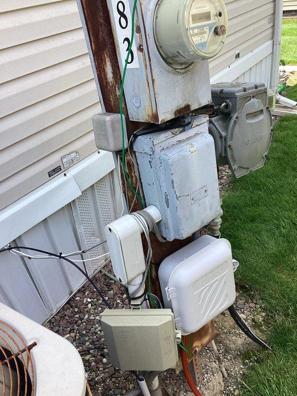 Completed air conditioning replacement estimate for residential property. Assessed existing outdoor condensing unit showing significant age-related deterioration, weathering, and exterior component wear. Unit positioned on concrete pad in narrow side yard with adequate clearance between structures. Evaluated electrical service including meter, disconnect box, and associated wiring mounted on utility pole, noting visible rust and aging on existing electrical panel components. Documented current system configuration and site conditions through photographs for estimate preparation. Homeowner to review replacement options and make final decision regarding equipment selection and installation scope.