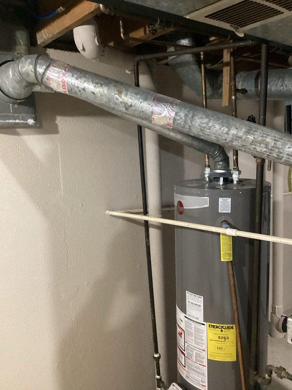 Completed comprehensive HVAC system evaluation for air conditioning replacement estimate in residential basement utility area. Assessed existing ComfortMaker furnace unit, ductwork configuration, and mechanical room layout to determine optimal replacement equipment specifications and installation requirements. Documented current system conditions including insulated ductwork, copper piping connections, and clearance parameters for new AC equipment installation.