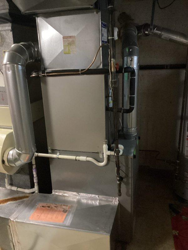 Conducted comprehensive assessment of non-functional air conditioning system and existing furnace installation located in basement utility area. Evaluated outdoor condenser unit positioned against exterior brick wall, documented current equipment configuration including ductwork, condensate drainage system, and electrical connections, and provided complete system replacement estimate for new HVAC equipment.