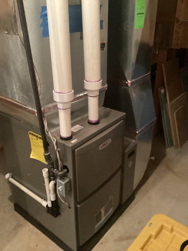Conducted comprehensive evaluation of 24-year-old original central air conditioning system experiencing mechanical rattling and inadequate cooling performance in upper-level living spaces. Assessed existing HVAC infrastructure including furnace unit, ductwork distribution system, and ventilation components in basement installation area. Documented current equipment condition, identified insufficient cooling capacity to second-floor bedrooms, and photographed system configuration including PVC venting assembly, metallic duct runs throughout exposed ceiling joists, and overall mechanical layout to provide detailed replacement estimate for new central air unit.