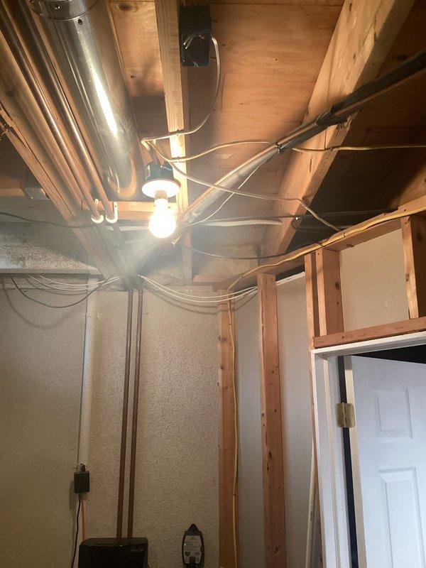 Conducted comprehensive evaluation of 24-year-old original central air conditioning system experiencing mechanical rattling and inadequate cooling performance in upper-level living spaces. Assessed existing HVAC infrastructure including furnace unit, ductwork distribution system, and ventilation components in basement installation area. Documented current equipment condition, identified insufficient cooling capacity to second-floor bedrooms, and photographed system configuration including PVC venting assembly, metallic duct runs throughout exposed ceiling joists, and overall mechanical layout to provide detailed replacement estimate for new central air unit.