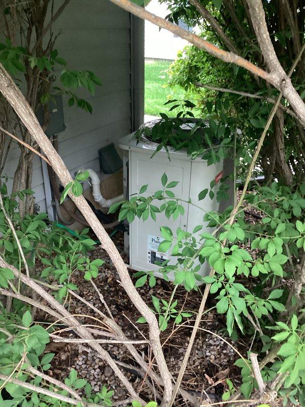 Conducted replacement estimate for a 24-year-old non-operational air conditioning system located on exterior of residence. Unit positioned in landscaped area with surrounding vegetation, accessible via side yard with established concrete pad. Documented existing equipment condition, photographed current installation including condenser unit and associated piping, and assessed site requirements for complete system replacement.