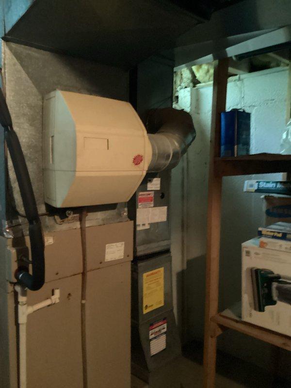Provided estimate for complete HVAC system replacement of 1992 equipment located in basement mechanical room. Current air conditioning unit operational but not cooling effectively due to age and system deterioration. Assessed existing natural gas furnace with drum-style humidifier, air handler, and aging ductwork showing significant wear, discoloration, and staining throughout attic installation, indicating compromised system efficiency and need for full system upgrade.