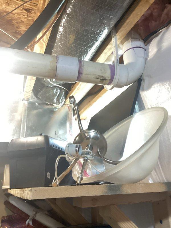 Conducted comprehensive evaluation of 12-year-old air conditioning system for replacement estimate. Inspected existing outdoor condenser unit and indoor air handler components, including ductwork, condensate drainage system with PVC piping, and attic-mounted HVAC equipment. Documented current system configuration with photographs showing air handler installation, metallic ductwork with foil backing, white PVC condensate lines with proper drainage routing, and mounting infrastructure in confined attic space. Assessed system accessibility, existing electrical connections, and refrigerant line routing to determine replacement requirements and equipment specifications for new installation.