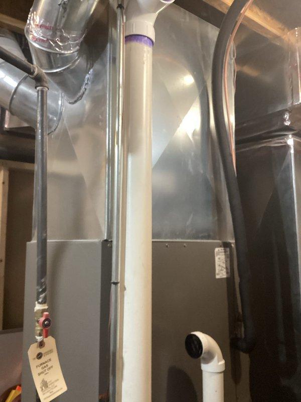 Conducted comprehensive evaluation of 12-year-old air conditioning system for replacement estimate. Inspected existing outdoor condenser unit and indoor air handler components, including ductwork, condensate drainage system with PVC piping, and attic-mounted HVAC equipment. Documented current system configuration with photographs showing air handler installation, metallic ductwork with foil backing, white PVC condensate lines with proper drainage routing, and mounting infrastructure in confined attic space. Assessed system accessibility, existing electrical connections, and refrigerant line routing to determine replacement requirements and equipment specifications for new installation.