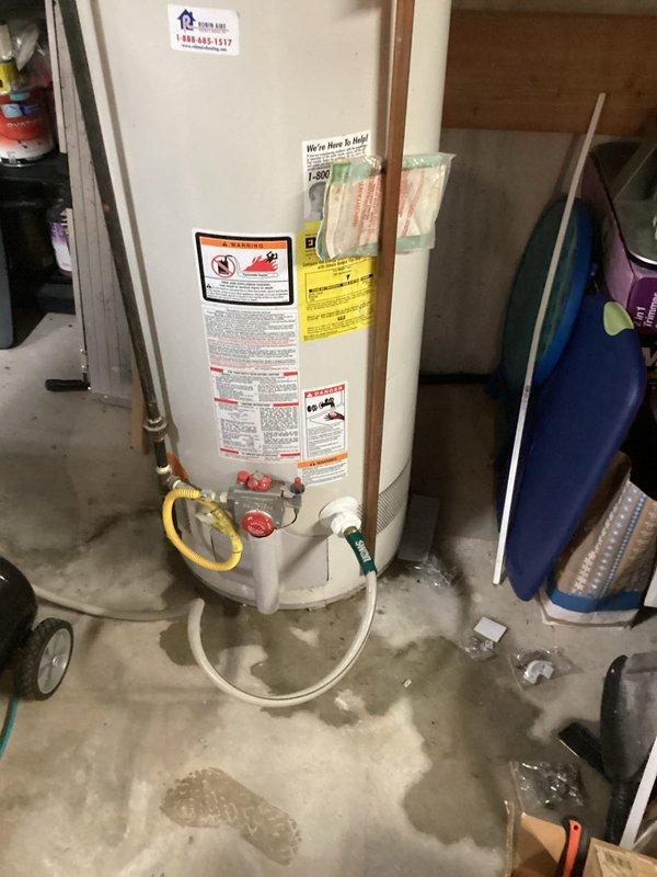 Performed water heater replacement estimate for leaking GE SmartWater residential tank-style unit showing moisture staining at base. Assessed existing installation including copper supply lines, yellow-handled shutoff valve, flexible connections, and venting system to provide replacement specifications before failure causes significant water damage.