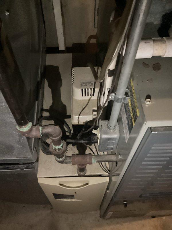 Performed comprehensive assessment of existing HVAC system for replacement estimate due to failed compressor and deteriorated equipment condition. Evaluated air handler unit in attic space showing significant condensation accumulation on cabinet and connected ductwork, indicating potential insulation deficiencies and system inefficiencies. Inspected basement mechanical equipment including furnace/air handler with aging copper refrigerant lines displaying oxidation and compression fittings with visible wear. Documented extensive moisture presence on metal surfaces and assessed overall system age and condition rating of 2-4, confirming replacement recommendation over repair due to compressor failure and compromised equipment integrity. Photographed existing installation configuration, ductwork routing, and component conditions to support replacement proposal specifications.