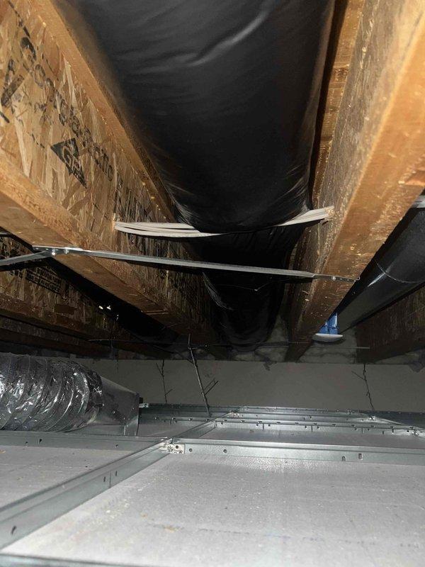 Responded to service call for clicking noise from compressor and moisture discharge from supply vents on one-year-old system. Inspected outdoor condensing unit and confirmed clicking sound during compressor cycling, determined to be normal relay operation within acceptable parameters. Investigated moisture complaint and identified inadequate duct insulation in unconditioned space allowing condensation formation on cold supply ductwork. Documented existing insulation deficiencies with photos showing exposed and improperly wrapped ductwork in attic/crawl space area. Recommended additional insulation wrap and proper vapor barrier installation on supply ducts to eliminate condensation issues. System operating and providing adequate cooling at time of inspection.