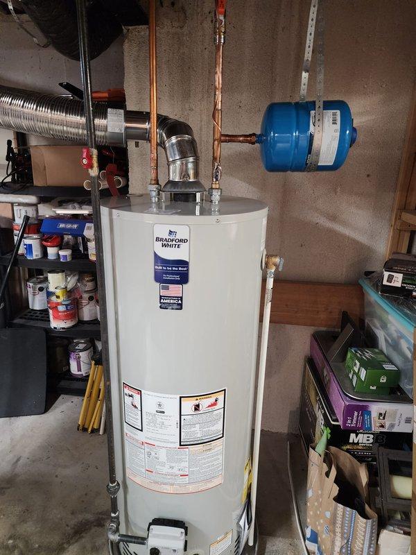 Installed a 50-gallon Bradford White natural draft water heater in basement utility area. Connected copper supply lines with shut-off valves, installed blue expansion tank on wall mount, and configured proper venting through existing ductwork to ensure safe exhaust operation.