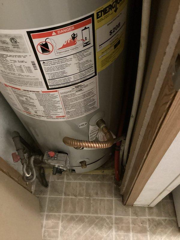 Performed replacement estimate for 20-year-old residential water heater experiencing degraded performance with rusty and odorous water output. Inspected existing unit installed in utility closet, documented current installation including plumbing connections, safety labels, and gas line configuration. Verified serial number SC411405569 indicating possible March 2018 manufacture date, assessed condition of surrounding components including shut-off valves and flexible connectors to provide accurate replacement specifications.