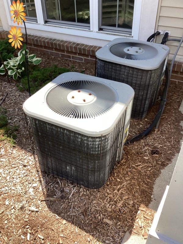 Provided comprehensive estimate for complete air conditioning system replacement on 20-year-old unit currently in operational condition. Evaluated existing indoor air handler located in basement utility area with associated ductwork infrastructure and outdoor condenser units positioned on exterior mulched pad adjacent to building foundation. Assessment included documentation of dual outdoor condensers, flexible and rigid ductwork configurations, refrigerant line routing, and electrical connections to determine optimal replacement specifications and installation requirements.