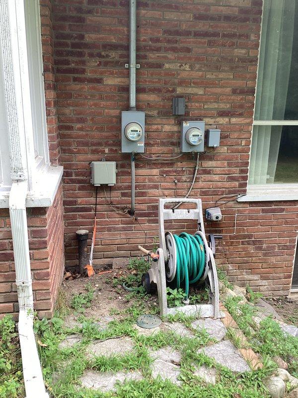 Conducted comprehensive site assessment and electrical estimate for generator installation at brick commercial building. Evaluated existing electrical infrastructure including dual meter configuration, surface-mounted conduit system, and main distribution panel with approximately 10-12 circuit positions in utility area. Documented current electrical service entrance equipment, junction boxes, and wire routing to determine optimal generator integration points and transfer switch placement requirements. Photographed exterior electrical components mounted on brick facade and interior breaker panel on concrete block wall to assess load capacity and identify necessary upgrades for automatic transfer switch installation and generator connectivity.