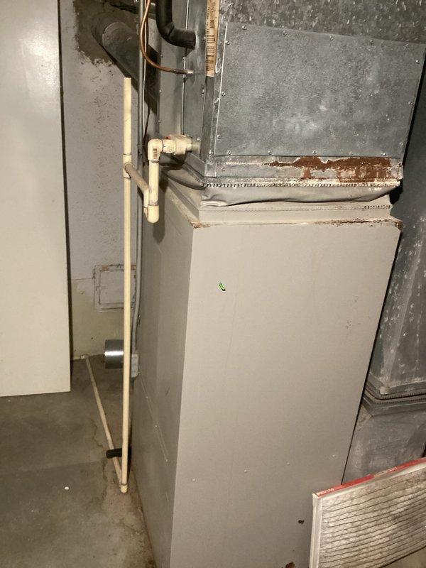 Responded to service call for 28-year-old central air conditioning system not cooling and affecting entire home. Upon arrival, inspected outdoor condensing unit manufactured in 1998 and indoor air handler unit dating to 1985, both utilizing obsolete R-22 refrigerant. Documented existing HVAC infrastructure in basement location, including aged air handler with visible corrosion and rust deterioration along panel seams and horizontal joints. Photographed gray metal ductwork, plenum assembly, and associated refrigerant lines. Noted PVC condensate drain lines and copper refrigerant piping configuration. Assessed overall system condition, confirming equipment has exceeded typical service life expectancy and operates on phased-out R-22 refrigerant, making repairs increasingly cost-prohibitive. Provided comprehensive replacement estimate for complete HVAC system upgrade to modern, energy-efficient equipment with current refrigerant technology.